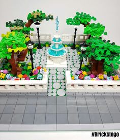 a lego model of a garden with trees, flowers and a fountain in the center