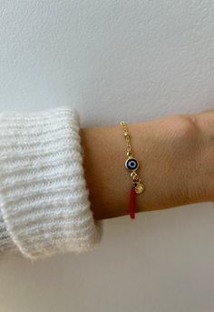 Keep yourself  protected with this evil eye bracelet that also combines a red string . D E T A I L S *It combines a high quality 18k gold filled satellite chain and  a twisted cotton cord measuring 1.5mm . *The focal point  is an 18k gold filled evil eye charm in traditional navy blue.  Charm measures 6mm. *A small gold filled hammered circle charm hangs down adding a pretty detail. *It closes with a hall marked gold filled spring ring clasp measuring 6mm. *Bracelet comes with an explanatory card and is gift ready. S I Z I N G * H E L P This bracelet works best with a snug fit which means measuring your wrist exactly and to this adding 1/2 inch to account for flex. See chart. C A R E * T I P :  To keep your bracelet in great condition avoid contact with water, perfume and chemicals. Also r Bracelet With Meaning, Red String Of Fate Bracelet, Evil Eye Bracelet Gold, String Of Fate, Red String Of Fate, Bracelet Evil Eye, Turkish Eye, Bracelets With Meaning, Blue Charm