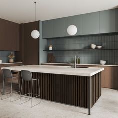 a modern kitchen with an island and bar stools in the center, along with two hanging lights