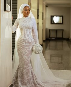 a woman in a wedding dress standing next to a wall with a veil on her head