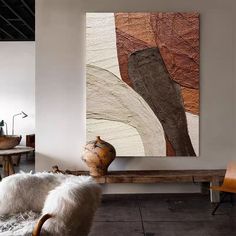 an abstract painting hangs on the wall above a wooden bench in a living room with two chairs