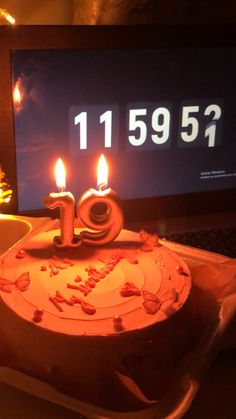 a birthday cake with lit candles sitting in front of a laptop