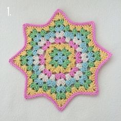 a crocheted square is shown with the center in pink, yellow and green