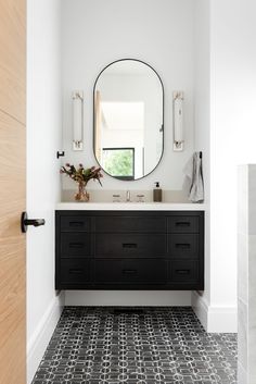 a black and white bathroom with a round mirror