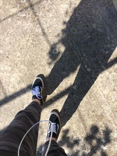 the shadow of a person standing next to a skateboarder on concrete with their feet up