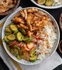 two plates filled with rice, vegetables and chicken