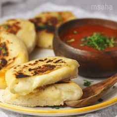 some food is sitting on a plate next to a bowl of soup and a spoon