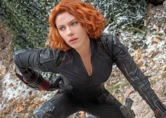 a woman with red hair and black leather outfit posing for the camera in front of snow covered rocks