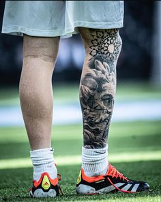 the legs and ankles of a man with tattoos on his body, wearing running shoes