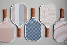 four paddles with different designs on them are lined up in a row against a gray background