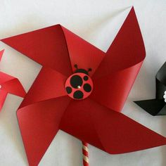 a red pinwheel with a ladybug on it next to another pinwheel