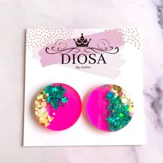 pair of pink and green earrings with glitters on them sitting on top of a card