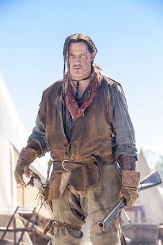 a man in an old fashioned outfit holding a baseball bat and looking at the camera