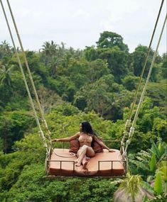 a woman sitting on top of a zip line in the jungle