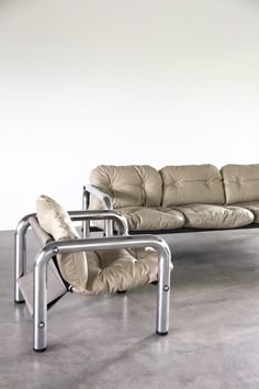 two leather couches sitting next to each other in a room with concrete flooring