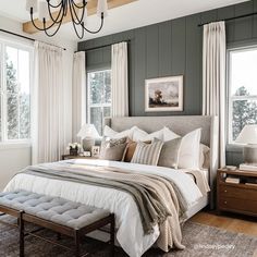 a bedroom with gray walls, white bedding and a chandelier hanging from the ceiling