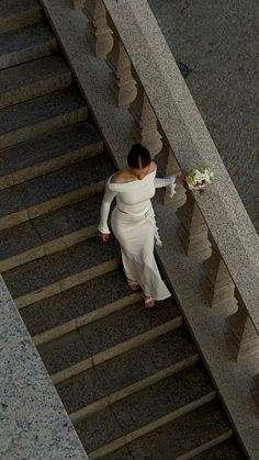 a woman in a white dress is walking down the stairs