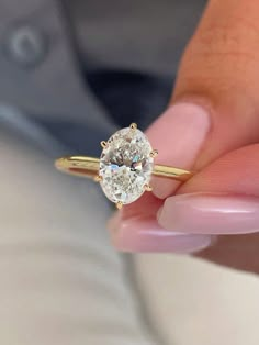 a close up of a person's hand holding a ring with a diamond on it