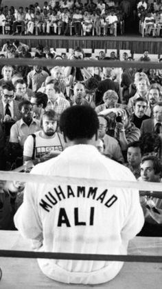 a black and white photo of a man holding a baseball bat in front of a crowd