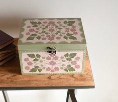 a green and pink box sitting on top of a wooden table next to two books