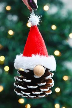 a pine cone ornament with a santa hat hanging from it's side