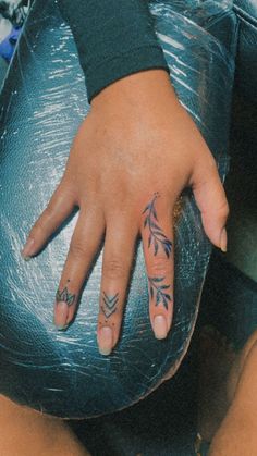 a woman's left hand with tattoos on it