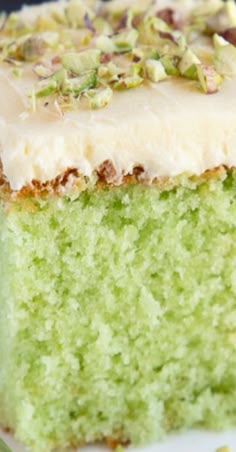 a piece of green cake with white frosting and pistachio sprinkles