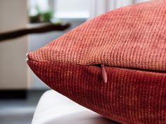 a red pillow sitting on top of a white chair