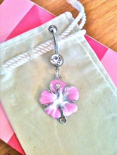 a pink flower is hanging from a white string on a beige bag next to some cards