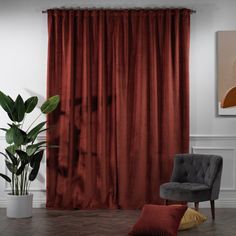 a living room with a chair, potted plant and red curtains