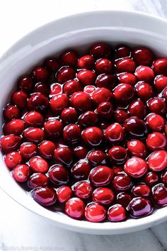 a white bowl filled with cherries on top of a table