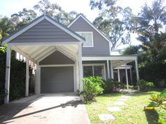 a gray house with a white roof and two car garages on the side of it