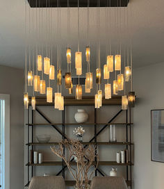 a dining room table with chairs and lights hanging from the ceiling