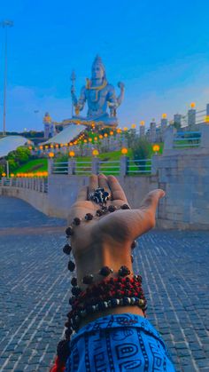 a person with their hand up in the air near a buddha statue at night time