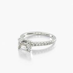 an emerald cut diamond engagement ring on a white background