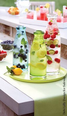 several bottles filled with fruit sitting on top of a table next to plates and bowls