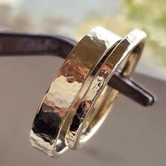 two gold and silver rings sitting on top of each other in front of a window