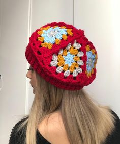 a woman with blonde hair wearing a red crocheted hat