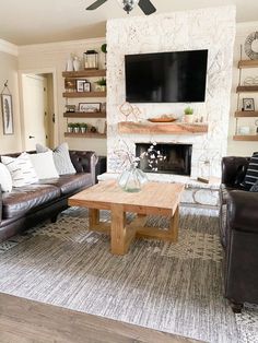 a living room with two couches and a tv mounted on the wall above it