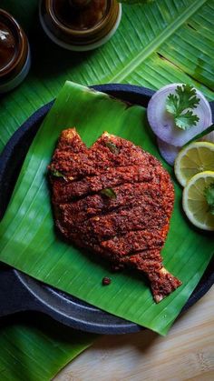 a heart shaped piece of meat sitting on top of a green plate next to sliced lemons