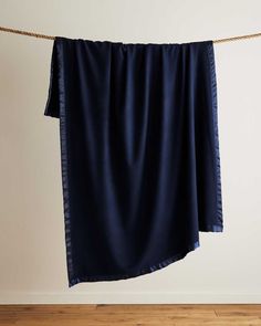 a blue blanket hanging on a rope in front of a white wall and wooden floor