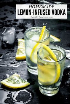 two glasses filled with lemon - infused vodka sitting on top of a black table next to sliced lemons