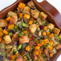 a brown bowl filled with stuffing and vegetables