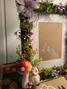 a mushroom and toad figurine sitting in front of a frame with flowers on it