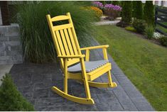 a red rocking chair sitting on top of a brick patio next to a green lawn