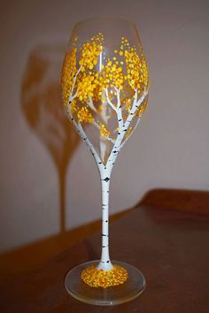 a wine glass decorated with yellow and white leaves