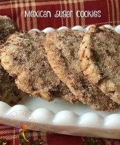 mexican sugar cookies on a white platter with red and yellow plaid cloth in the background