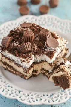 a piece of cake on a white plate with chocolate chips and oreo cookies in the background