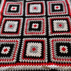 a crocheted blanket with red and black squares