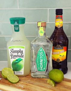 the ingredients to make an easy margarita cocktail are displayed on a cutting board with limes